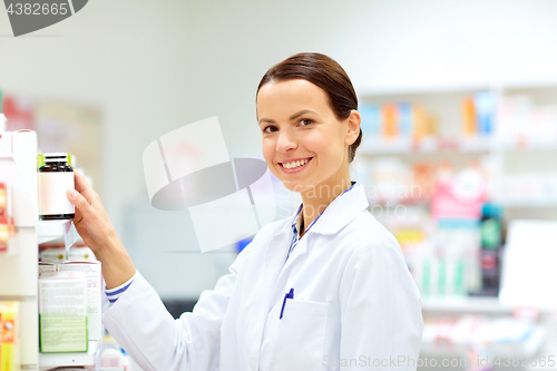 Image of happy female apothecary with drug at pharmacy