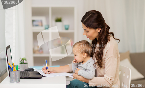 Image of happy mother with baby and papers working at home