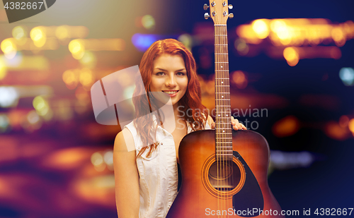 Image of female musician with guitar over night city lights