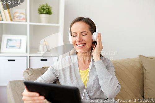 Image of happy woman with tablet pc and headphones at home