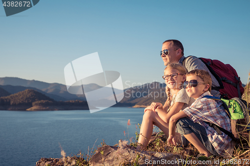 Image of Happy family sitting near a lake at the day time.