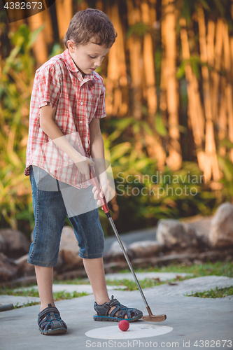 Image of Happy little boy  playing mini golf.