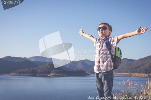 Image of One happy little boy standing near a lake