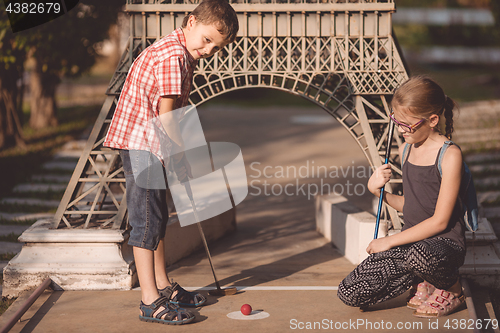 Image of Happy brother and sister  playing mini golf.