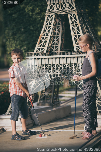 Image of Happy brother and sister  playing mini golf.