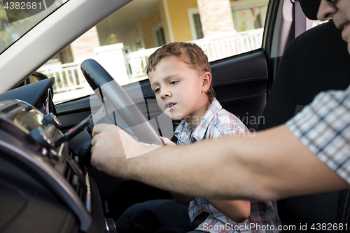 Image of Happy father and son sitting in the car at the day time.