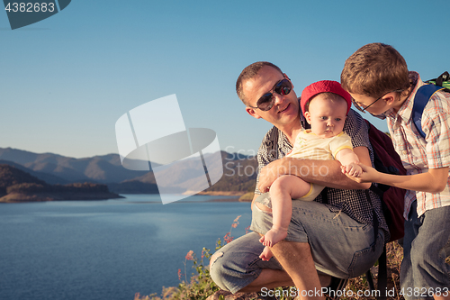 Image of Happy family sitting near the lake at the day time.