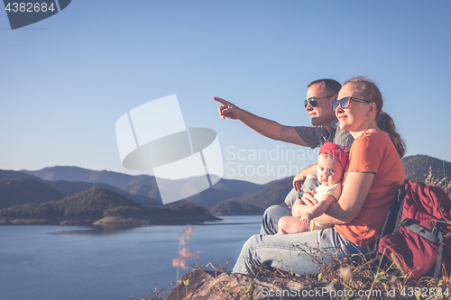 Image of Happy family sitting near the lake at the day time.