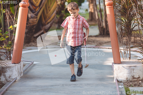 Image of Happy little boy  playing mini golf.