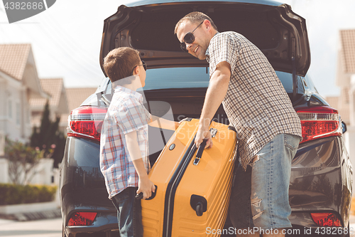 Image of Happy father and son getting ready for road trip on a sunny day.