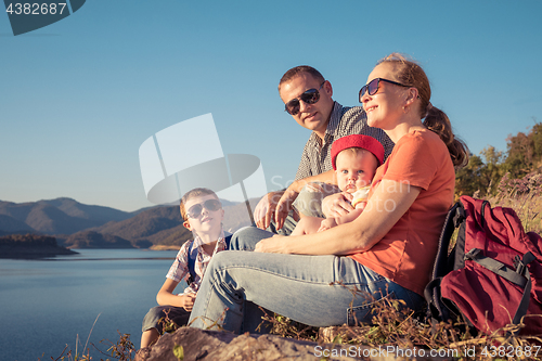 Image of Happy family sitting near the lake at the day time.