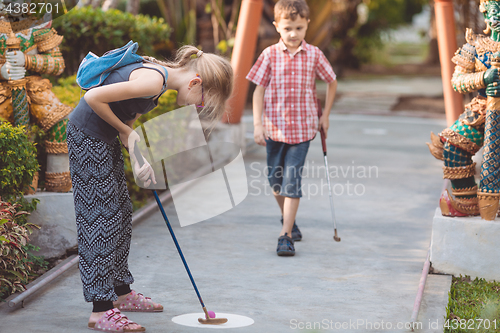 Image of Happy brother and sister  playing mini golf.