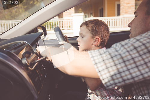 Image of Happy father and son sitting in the car at the day time.