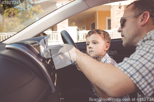 Image of Happy father and son sitting in the car at the day time.