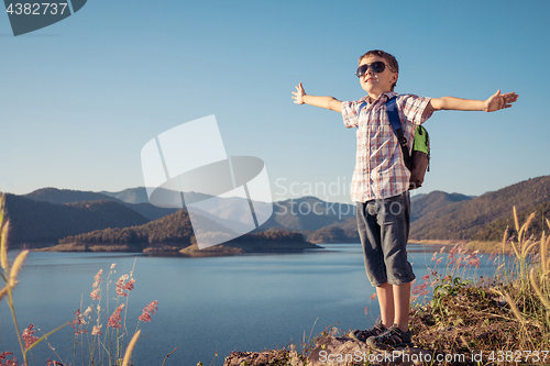 Image of One happy little boy standing near a lake