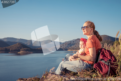 Image of Happy family sitting near a lake at the day time.