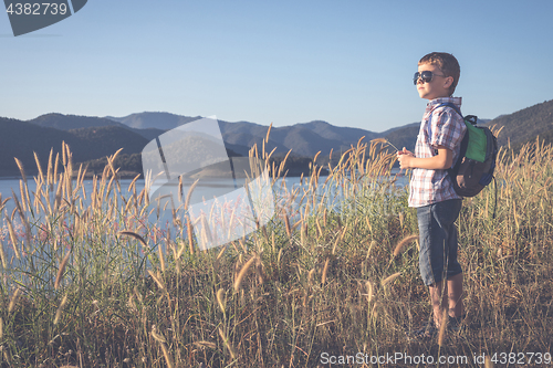 Image of One happy little boy standing near a lake