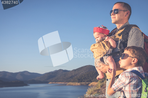 Image of Happy family standing near the lake at the day time.