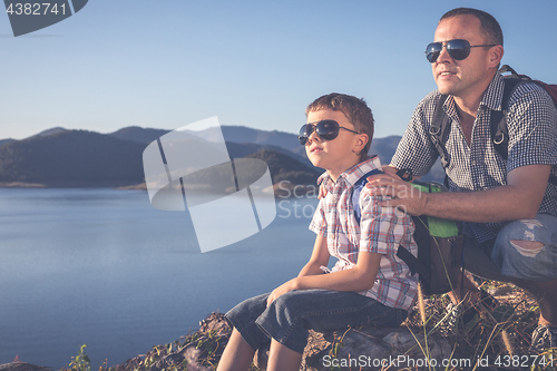 Image of Happy family sitting near a lake at the day time.