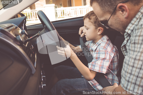 Image of Happy father and son sitting in the car at the day time.