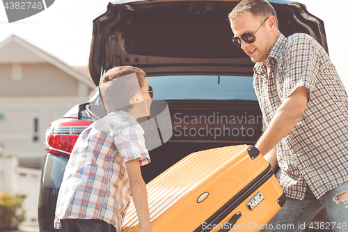 Image of Happy father and son getting ready for road trip on a sunny day.