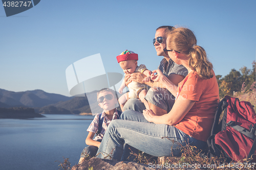 Image of Happy family sitting near the lake at the day time.