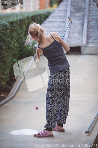 Image of Happy little girl  playing mini golf.