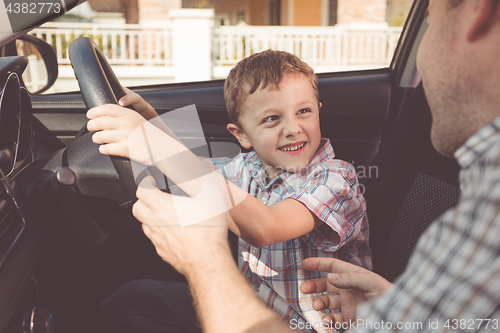 Image of Happy father and son sitting in the car at the day time.