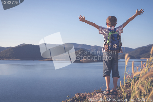 Image of One happy little boy standing near a lake