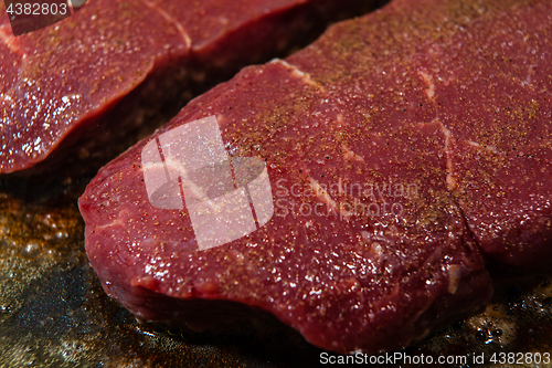 Image of A juicy steak seasoned with pepper ready to be fried