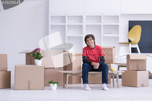 Image of boy sitting on the table with cardboard boxes around him