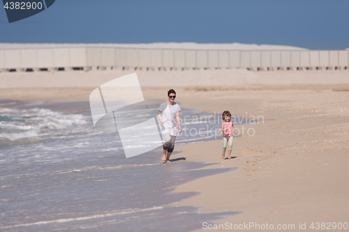 Image of mother and daughter running on the beach