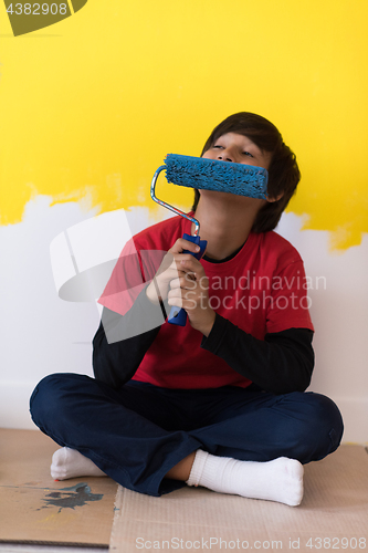 Image of young boy painter resting after painting the wall