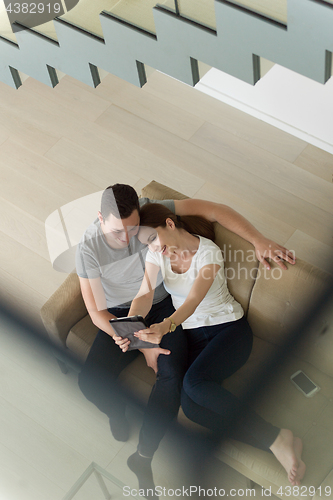 Image of couple relaxing at  home with tablet computers