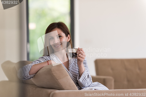 Image of young woman in a bathrobe enjoying morning coffee