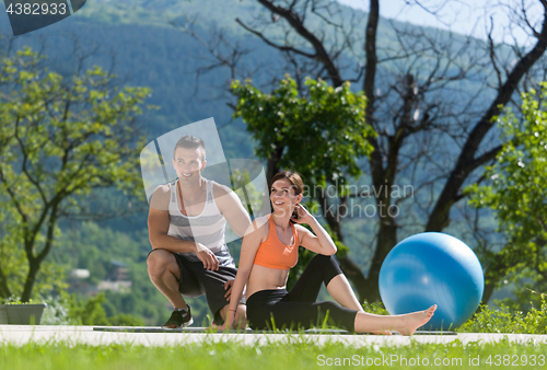 Image of woman with personal trainer doing morning yoga exercises