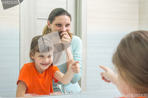 Image of My daughter and mother are having fun looking at my mother, who put her hair to her face like a mustache