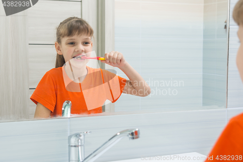 Image of Girl waking up in the morning brushing her teeth in the bathroom