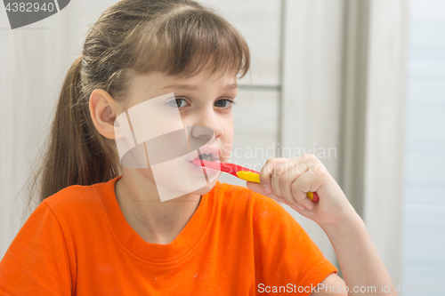 Image of The girl is brushing her teeth in the bathroom
