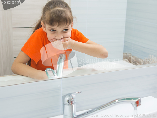 Image of The girl rinses her mouth after brushing her teeth