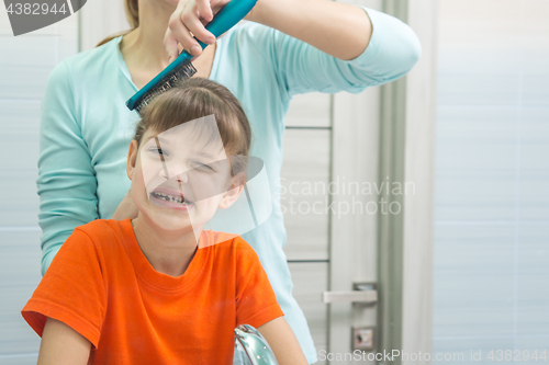 Image of Mom combs her seven-year-old daughter in the bathroom