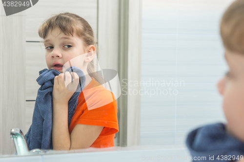 Image of Seven-year-old girl wipes her face with a towel after washing