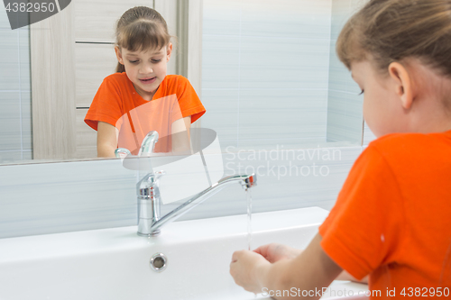 Image of Seven-year-old girl washes face in bath