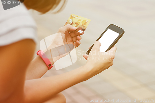 Image of Woman using phone and card for shopping