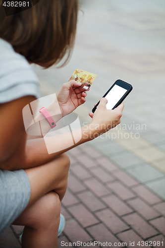 Image of Woman using phone and card for shopping