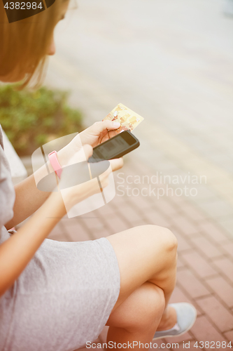 Image of Woman using phone and card for shopping