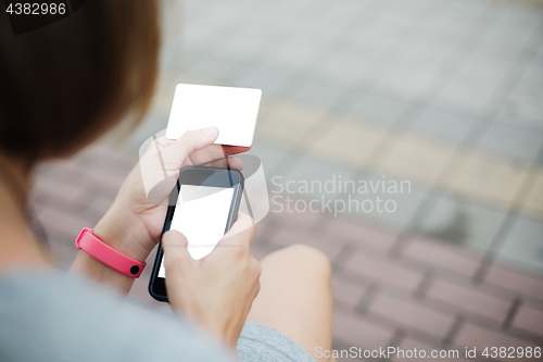 Image of Woman using phone and card for shopping