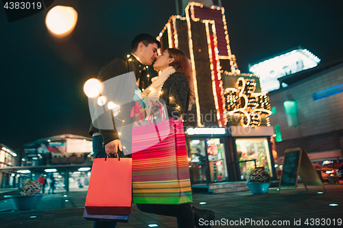 Image of The happy couple with shopping bags enjoying night at city background