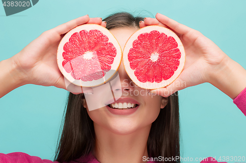 Image of Pretty woman with delicious grapefruit in her arms.