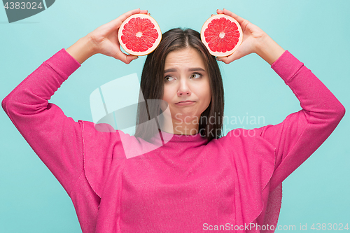 Image of Pretty woman with delicious grapefruit in her arms.